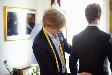 Fashion designer measuring male customer's back in boutique