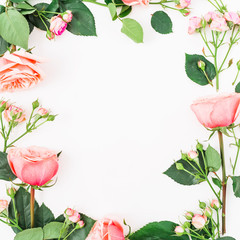Flat lay, top view. Floral frame made of pink roses, leaves and buds on white background.