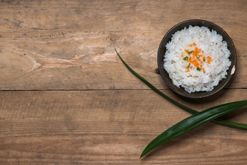 Boiled rice in a bowl on wooden table.