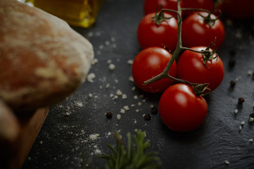 Cucina mediterranea, pomodorini, olio, sale, asparagi su fondo lavagna