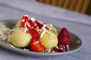 Traditional czech dish. Quark dough dumplings with fruit filling, These are with strawberries. Topped with grated quark,powdered sugar,sliced strawberries and melted butter.