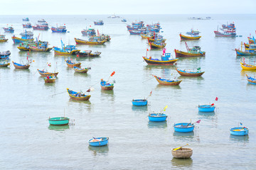 Fototapeta na wymiar Mui Ne, Vietnam - February 19th, 2017: Fishing village and traditional Vietnamese fishing boats with hundreds of boats moored in a line beautifully. This is the bay for boat storm in central Vietnam