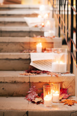 the stage decorated with white candles in glass candlesticks and yellow leaves