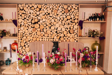 decorated wooden table with candles in glass candle holders, fruits in gold paint and a beautiful bottle of red and white flowers