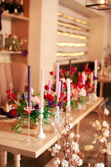 decorated wooden table with candles in glass candle holders, fruits in gold paint and a beautiful bottle of red and white flowers