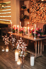 decorated wooden table with candles in glass candle holders, fruits in gold paint and a beautiful bottle of red and white flowers