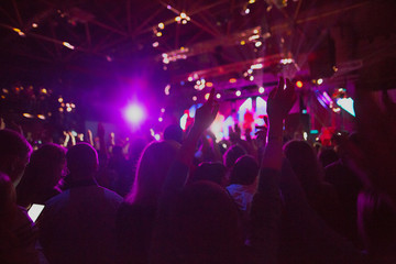 The silhouettes of concert crowd in front of bright stage lights