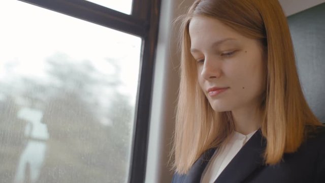 Young Beautiful Business Lady is Sitting by the Window in the Train and Typing Text on the Laptop