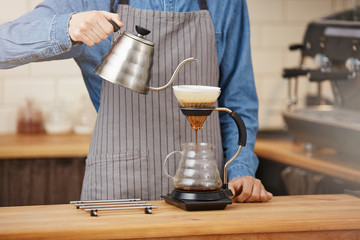 Bartender making alternative coffee using manual drip brewer, pouring water.