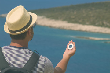 Hiker searching direction with compass near the sea shore