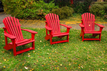 Wet Adirondack Chairs in a Lawn with Fallen Leaves on a Rainy Autumn Day.