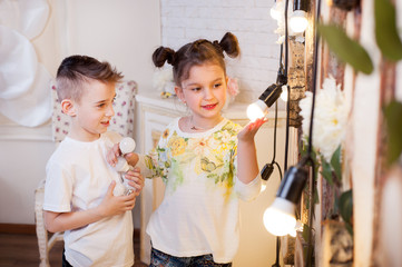 Little boy and girl play LED bulbs. They are holding light bulbs