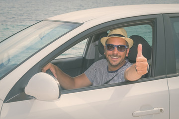 Naklejka premium Portrait of tourist car driver showing thumbs up. Travel and summertime concepts. 