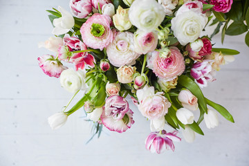  Flower arrangement with tulips and ranunculus on a white wooden floor. Spring flower 
