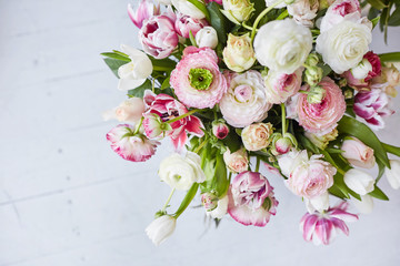  Flower arrangement with tulips and ranunculus on a white wooden floor. Spring flower 