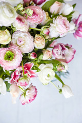  Flower arrangement with tulips and ranunculus on a white wooden floor. Spring flower 