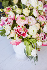  Flower arrangement with tulips and ranunculus on a white wooden floor. Spring flower 