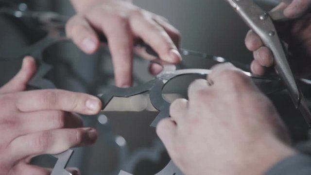 Close-up: artistic metal forging. Workers hold the metal part and give shape, using pliers (pasatis). Cylindrical shape of decorative metal element. Decorative metalworking.