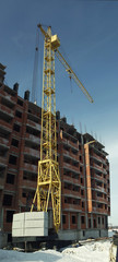 Fototapeta na wymiar Under construction high-rise building with yellow construction crane in the sunlight