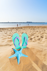 Summer beach fun - summer flip-flop sandals with starfish in beach sand