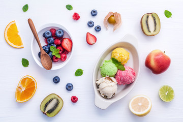 Colorful ice cream with mixed berry and various fruits raspberry ,blueberry ,strawberry ,orange slice ,apple,lemon and peppermint setup on white background . Summer and Sweet menu concept flat lay.