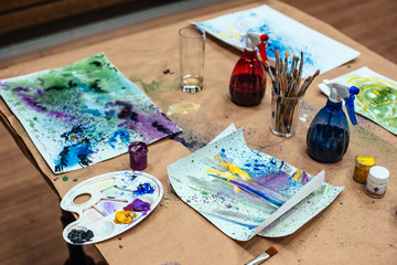 An painter table with paintings paint brushes and working tools 