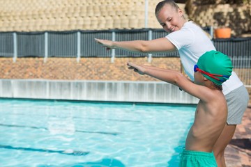 Female trainer training a boy for diving into pool