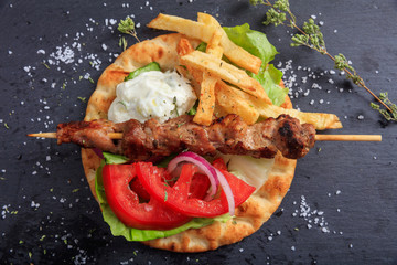 Grilled meat skewer on a pita bread - top view