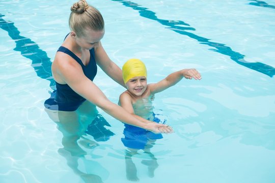 Female instructor training young boy in pool
