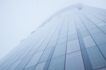 Fototapeta na wymiar Tall skyscraper disappears in the fog