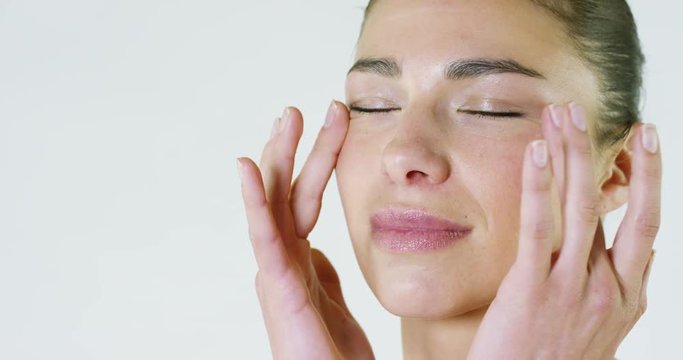 Portrait of a beautiful young girl who uses a cream for skin around the eyes,gives the skin of the most delicate face area a fresh and rested look, white background.Concept:bio products,spa procedures