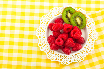Fresh Red Raspberries on a white artistic plate / Red Fresh Raspberries on a white artistic plate with cookies, rosemary, chocolate and cream in the background.