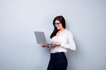 Photo of charming businesslady holding laptop and typing sms to her business colleagues