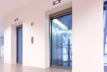 Fototapeta premium Two doors of elevators with transparent walls in modern business building