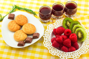 Fresh Red Raspberries on a white artistic plate / Red Fresh Raspberries on a white artistic plate with cookies, rosemary, chocolate and cream in the background.