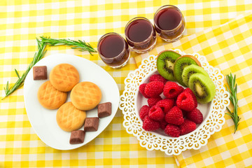 Fresh Red Raspberries on a white artistic plate / Red Fresh Raspberries on a white artistic plate with cookies, rosemary, chocolate and cream in the background.
