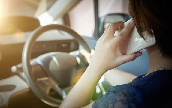 Woman driver using smart phone in car during traffic jam.