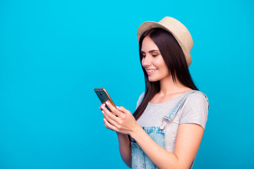 Naklejka premium Side view portrait of pretty young woman in summer hat sending sms to her best friend