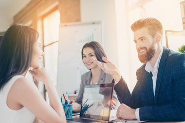 Obraz premium Business partners are smiling and discussing documents and ideas to solve problems of the company at meeting in bright workstation