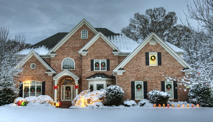 Beautiful brick estate home exterior in snow decorated for the holidays