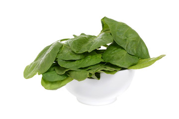 spinach leaves in a bowl isolated on white background