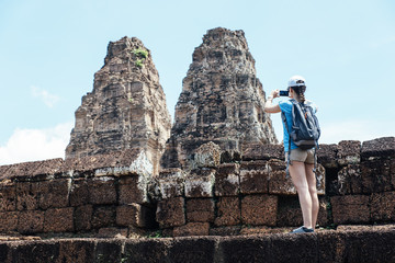 Woman taking picture to Angkor wat temple.
