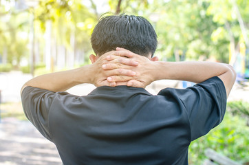 Rear view of a young man holding her neck in pain, monochrome photo with red as a symbol for the hardening.