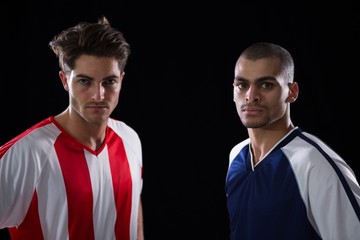 Two football players standing against black background