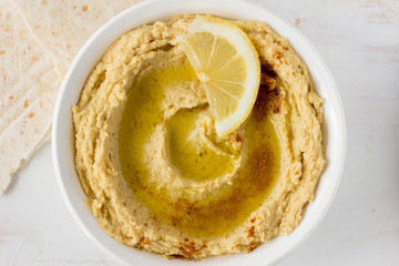 Hummus with spices and lemon in white bowl
