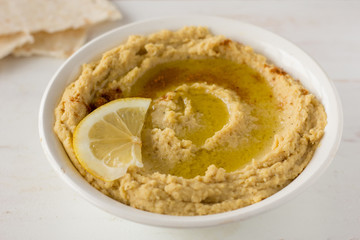 Hummus with spices and lemon in white bowl