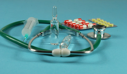 Stethoscope and syringe on blue background.