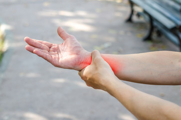 Fototapeta premium Pain in a man wrist. Male holding hand to spot of wrist pain in the park