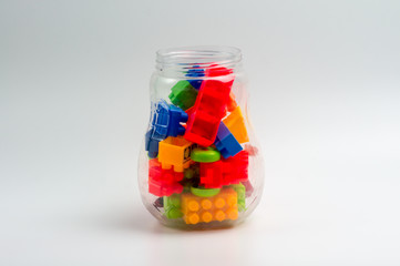 Multicolor plastic toy block in transparent plastic bottle isoltated on white background.