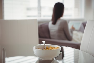 Close up of food in bowl against woman using tablet 